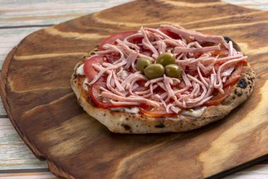 Ahşap bir tahtanın üzerinde mozarella domatesli roka jambonlu, ev yapımı, Napoli usulü pizzalar. 