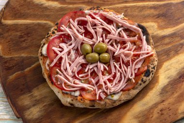 Ahşap bir tahtanın üzerinde mozarella domatesli roka jambonlu, ev yapımı, Napoli usulü pizzalar. 