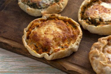 Ev yapımı hamurdan yapılmış ve içi tavuk, balkabağı, havuç, mozzarella, jambon ve peynirli ahşap bir tahtanın üzerinde.. 