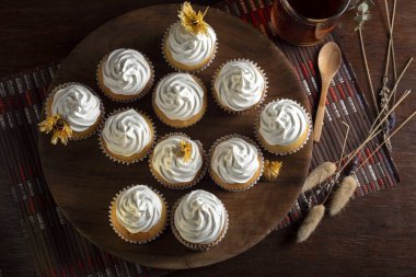 Kremalı kekler tepesinde eski çaydanlık çaydanlığı fincanı ile ahşap tabakta. 