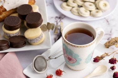 Kahvaltı ya da aperatif olarak bir bardak sütlü çay ile alfajore Madeleines tatlı kurabiyeler çikolata taze meyveler ve çeşitli kekler. 