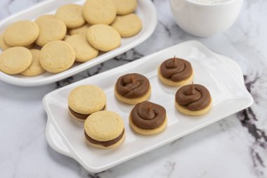 Koyu ve beyaz çikolatalı alfajore ve mısır nişastalı hindistancevizi rendelenmiş, kahvaltı masasında bir fincan süt ve kahve veya atıştırmalık 