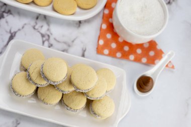 Koyu ve beyaz çikolatalı alfajore ve mısır nişastalı hindistancevizi rendelenmiş, kahvaltı masasında bir fincan süt ve kahve veya atıştırmalık 