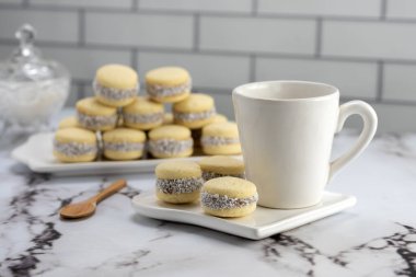 Koyu ve beyaz çikolatalı alfajore ve mısır nişastalı hindistancevizi rendelenmiş, kahvaltı masasında bir fincan süt ve kahve veya atıştırmalık 