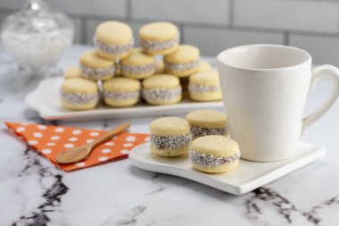 Koyu ve beyaz çikolatalı alfajore ve mısır nişastalı hindistancevizi rendelenmiş, kahvaltı masasında bir fincan süt ve kahve veya atıştırmalık 