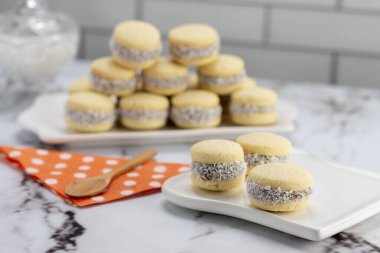 Koyu ve beyaz çikolatalı alfajore ve mısır nişastalı hindistancevizi rendelenmiş, kahvaltı masasında bir fincan süt ve kahve veya atıştırmalık 