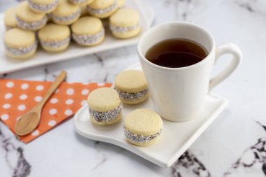 Koyu ve beyaz çikolatalı alfajore ve mısır nişastalı hindistancevizi rendelenmiş, kahvaltı masasında bir fincan süt ve kahve veya atıştırmalık 