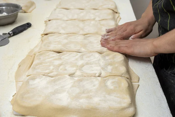 making homemade pasta hands filling the sorrentinos and stretching the dough into molds with the filling in a kitchen