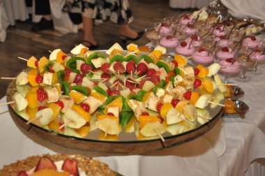 Pastalar meyveler ve şişler doğum günü için ve düğün kutlamaları tatlı yemek ve tatlı masasında süslemeli doğal çiçekler çikolatalı taze meyveler masanın üzerinde masa örtüsü ile  