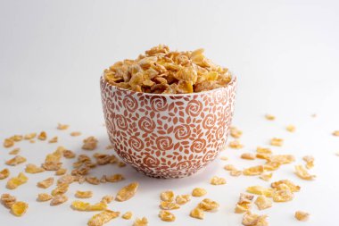 Sağlıklı ve besleyici mısır gevrekleri ile farklı renklerde seramik bardak beyaz arka planda 