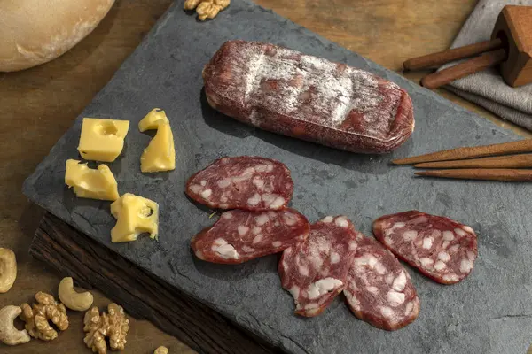 table of various cheeses and sausages and cut and chopped nuts ready to eat salami sausage blue cheese roquefort parmesan jammon and sausages still life photo