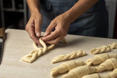 Ay çöreklerinin hamur işlerini adım adım yapan kadın ve erkek fırıncıların elleri, kruvasanları yoğurup pişirmeye hazır hale getiriyorlar.  