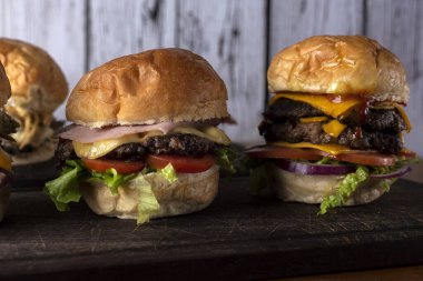 Ev yapımı taze et burgerler, patates ekmeği, yumurta pastırması, domates, soğan, çedar peyniri, jambon, farklı çeşitlerde patates kızartması ve fast food sosu. 