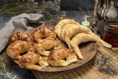 Çiğ ve pişmiş kruvasan ya da kahvaltıda tereyağı ve yağdan yapılmış kruvasan tepside ve masada atıştırmalık. 