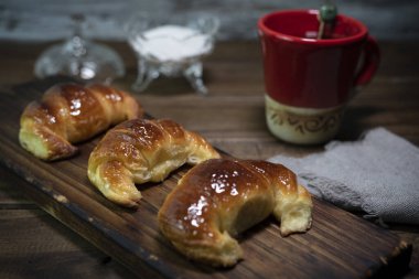 Çiğ ve pişmiş kruvasan ya da kahvaltıda tereyağı ve yağdan yapılmış kruvasan tepside ve masada atıştırmalık. 