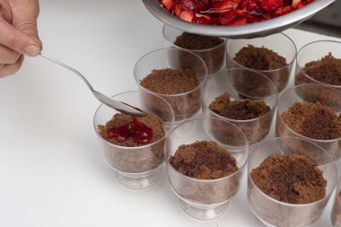 pastry woman assembling cakes and desserts step by step with fruits of the forest with cream decorating a cake and sweet glasses 