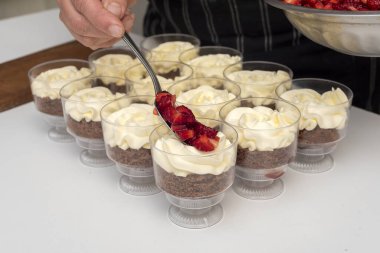 pastry woman assembling cakes and desserts step by step with fruits of the forest with cream decorating a cake and sweet glasses 