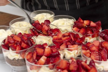 pastry woman assembling cakes and desserts step by step with fruits of the forest with cream decorating a cake and sweet glasses 