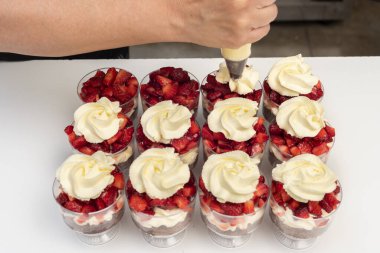pastry woman assembling cakes and desserts step by step with fruits of the forest with cream decorating a cake and sweet glasses 