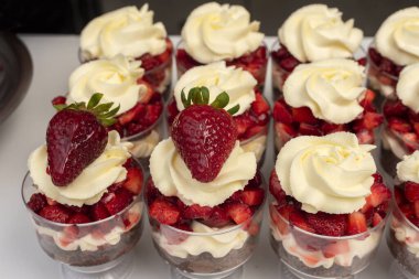 pastry woman assembling cakes and desserts step by step with fruits of the forest with cream decorating a cake and sweet glasses 