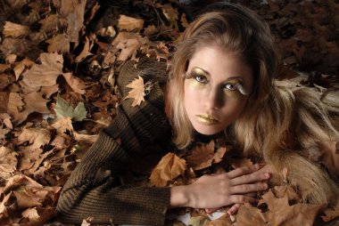 Sonbaharda yetişen genç bir kadın, yılın mevsimini kahverengi renklerle temsil eden bir ağacın kuru yapraklarıyla üretilmektedir. 