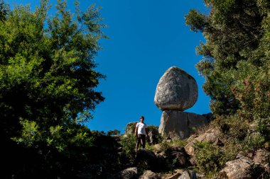 Dağlarda gezen genç bir adam kayalar ve serbest bitki örtüsü arasındaki büyük manzaranın tadını çıkarıyor. 
