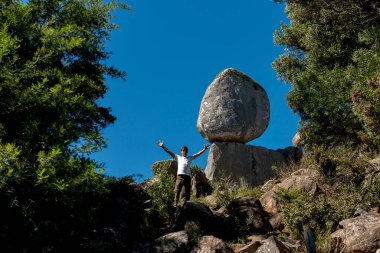 Dağlarda gezen genç bir adam kayalar ve serbest bitki örtüsü arasındaki büyük manzaranın tadını çıkarıyor. 