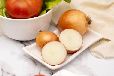 Salata, vejetaryen ve vejetaryen yemekleri için biber sirkesi ve tuzlu beyaz sofra takımında çeşitli sebzelerle masaya koyun. 