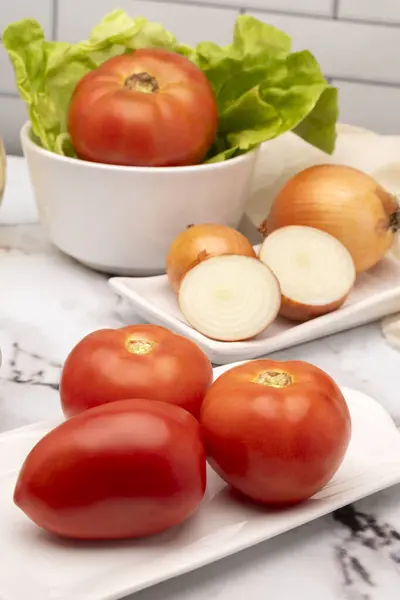 Salata, vejetaryen ve vejetaryen yemekleri için biber sirkesi ve tuzlu beyaz sofra takımında çeşitli sebzelerle masaya koyun. 