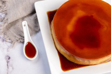 Homemade flan or Venezuelan cheese with whole caramel and in individual or large portions on white tableware  clipart
