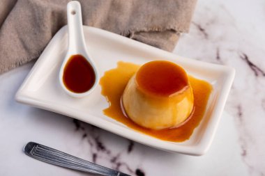 Homemade flan or Venezuelan cheese with whole caramel and in individual or large portions on white tableware  clipart