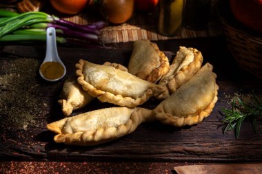 Ev yapımı et, tavuk, jambon ve peynirli börekler ahşap tahta, sebze ve baharatlar. 