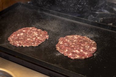 Ev yapımı hamburgerlerin pişirilmesi, montajlanması ve üretilmesi ve öğütülmüş et ve aşçıbaşı madalyonları adım adım yapıyor. 