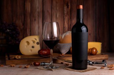 Bir kadeh kırmızı şarap, şarap şişesi, peynirli köy ekmeği, tahta tahta, üzüm bıçağı, mantar açacağı ve şişe. 