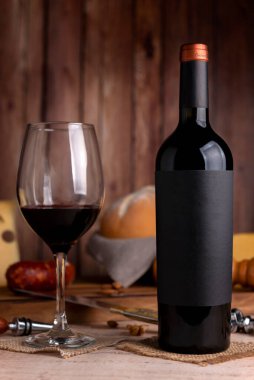 Bir kadeh kırmızı şarap, şarap şişesi, peynirli köy ekmeği, tahta tahta, üzüm bıçağı, mantar açacağı ve şişe. 