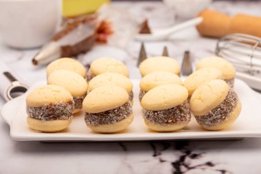 Ev yapımı mısır nişastası, yanında dulce de leche ve hindistan cevizi rendelenmiş Hindistan cevizi, içinde de un şekeri çırpılmış.