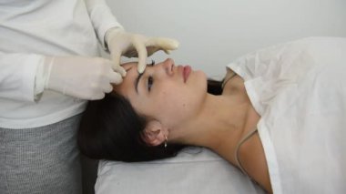 Güzellik merkezindeki bir masada oturan genç bir kadın deri yüzme tekniğini kullanarak yüz derisine güzellik tedavisi uyguluyor. 