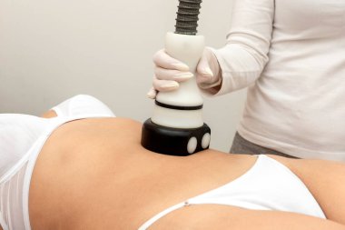 Bir güzellik uzmanının vücut ve sağlık için uyguladığı hifu ve velaslim tekniğiyle cildinde ve yüzünde estetik bir tedaviden geçen sedye taşıyan genç bir kadın.