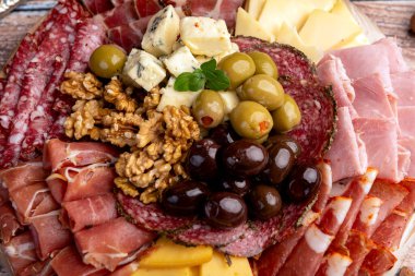 Çeşit çeşit peynirle servis edilen servis masası, sardunya peyniri ve kekik ve zeytin aromalı ev yapımı ekmek fileto, jambon, domuz omuzu, salam, fındıklı mortadella ve çeşitli sosisli sandviçler. 