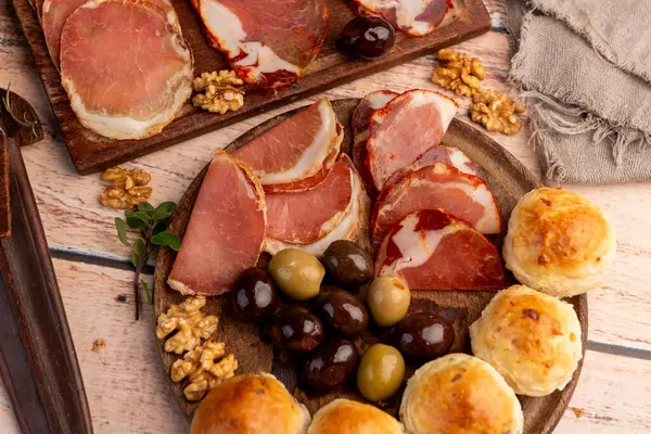 Çeşit çeşit peynirle servis edilen servis masası, sardunya peyniri ve kekik ve zeytin aromalı ev yapımı ekmek fileto, jambon, domuz omuzu, salam, fındıklı mortadella ve çeşitli sosisli sandviçler. 