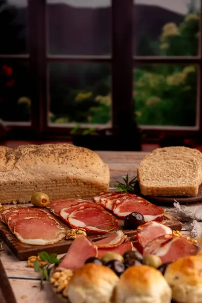 Çeşit çeşit peynirle servis edilen servis masası, sardunya peyniri ve kekik ve zeytin aromalı ev yapımı ekmek fileto, jambon, domuz omuzu, salam, fındıklı mortadella ve çeşitli sosisli sandviçler. 