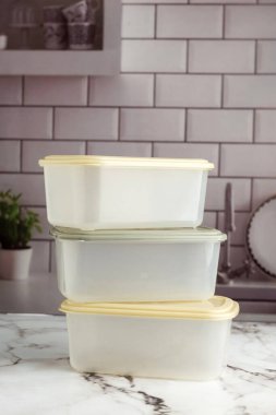 Mutfak tezgahında çok amaçlı plastik yiyecek kapları, sebzeler, etler, peynirler. 