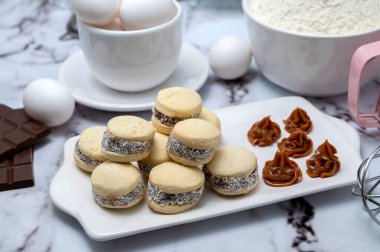 Malzeme ile tezgah: yumurta, un, çırpıcı, ve mısır nişastası alfajore dulce de leche ve hindistan cevizi, beyaz tabaklı çikolata