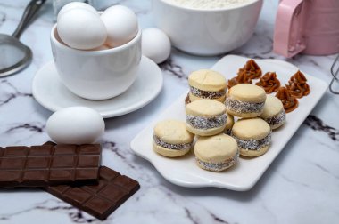 Malzeme ile tezgah: yumurta, un, çırpıcı, ve mısır nişastası alfajore dulce de leche ve hindistan cevizi, beyaz tabaklı çikolata