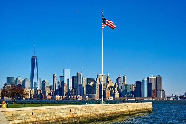New York. United States. Manhattan skyline from Liberty Island. American flag - Date: 03 - 01 - 2022