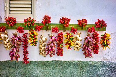 Vieste Gargano. Apulia Puglia İtalya. Kırmızı biber, arpacık soğanı ve sarımsak bir evin önünde kuruması için asıldı. Tarih: 01 - 09 - 2023