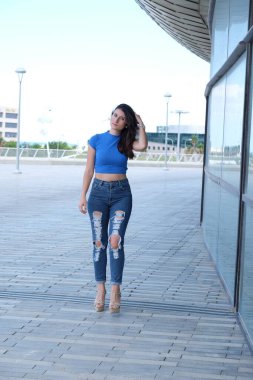 Şehirde kot pantolon ve siyah elbise giyen genç bir kız.