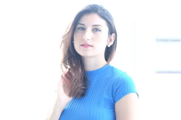 Beyaz arka planda, mavi kazaklı güzel bir kız.