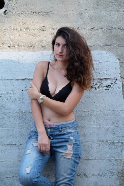 Eski beton duvarın arkasında poz veren genç bir kadın.