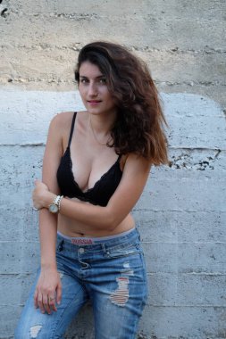 Beyaz bluzlu, beyaz şortlu, şehir ortamında poz veren beyaz bir kadının dikey çekimi.